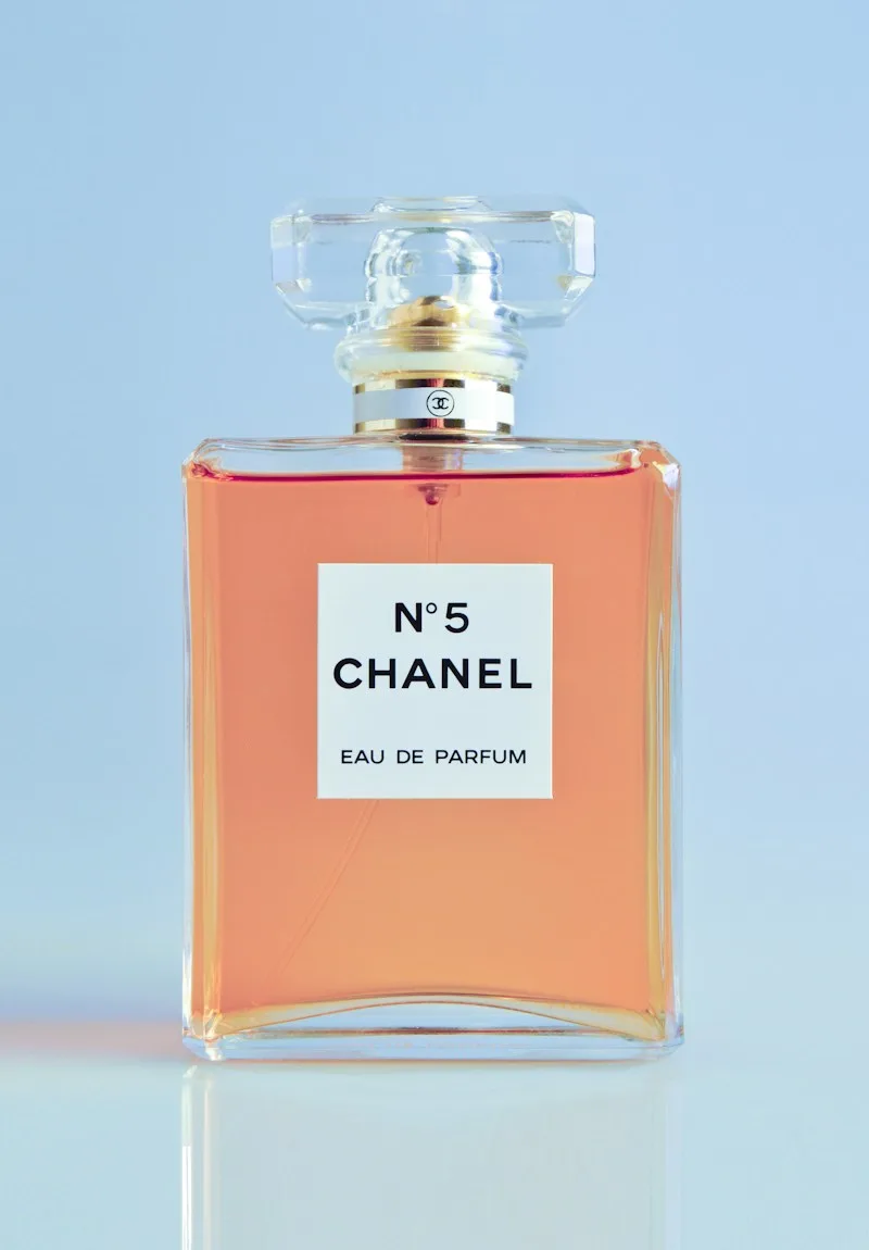 Chanel N°5 perfume bottle against a pale blue background.