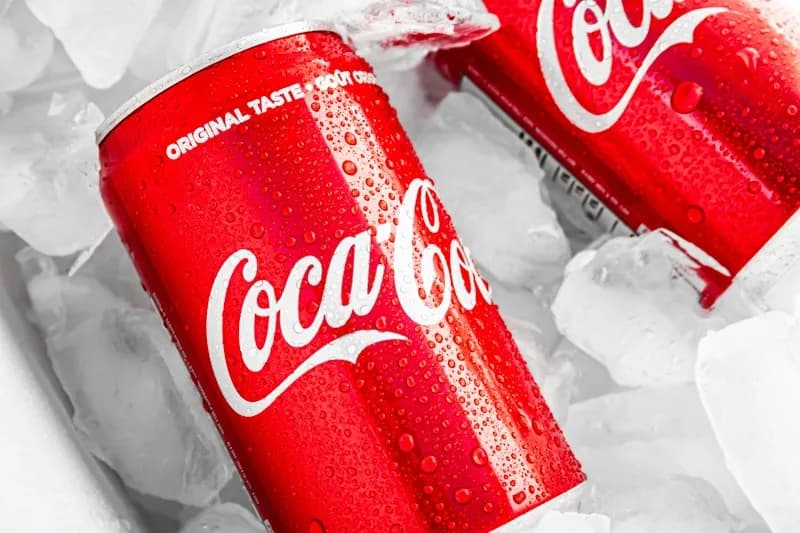 Coca-Cola cans with water droplets resting in ice.