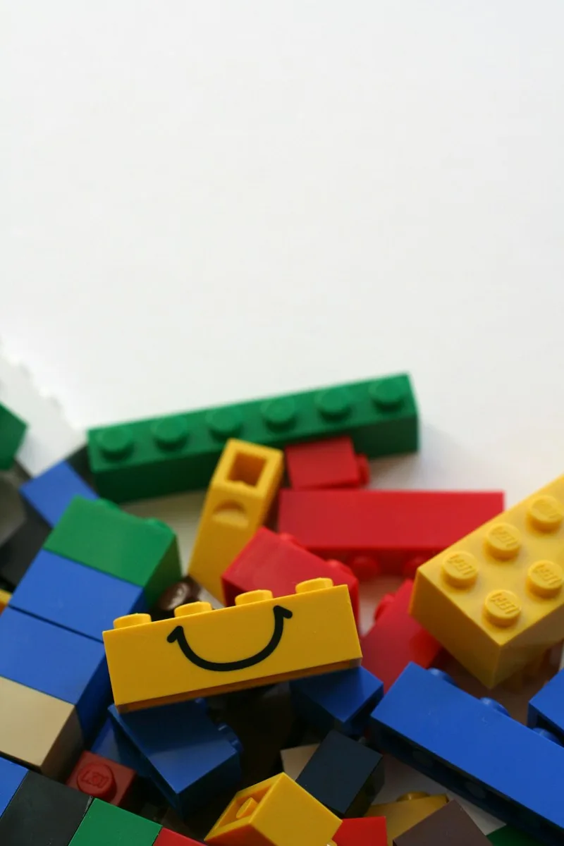 Colorful LEGO bricks, including a yellow smiling brick.