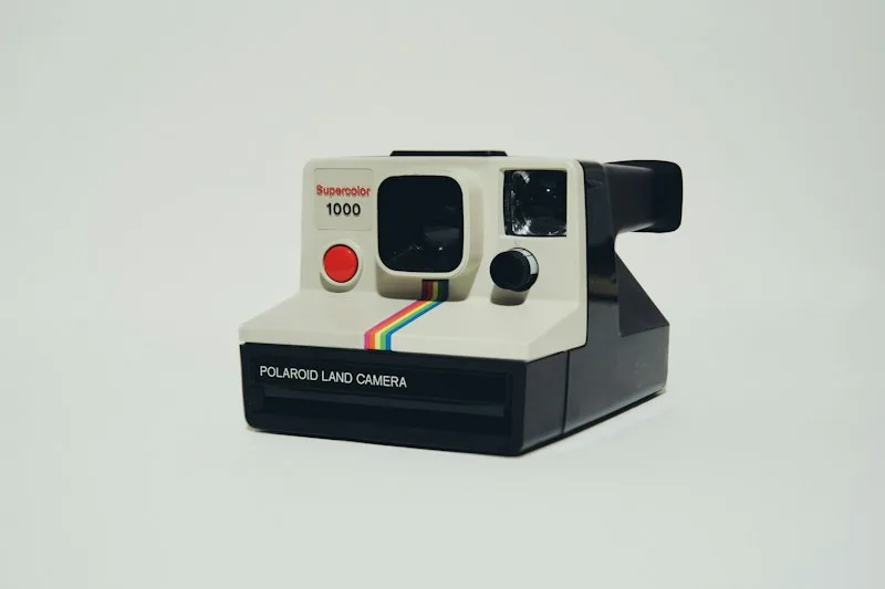 Vintage Polaroid instant camera on a pale green surface.