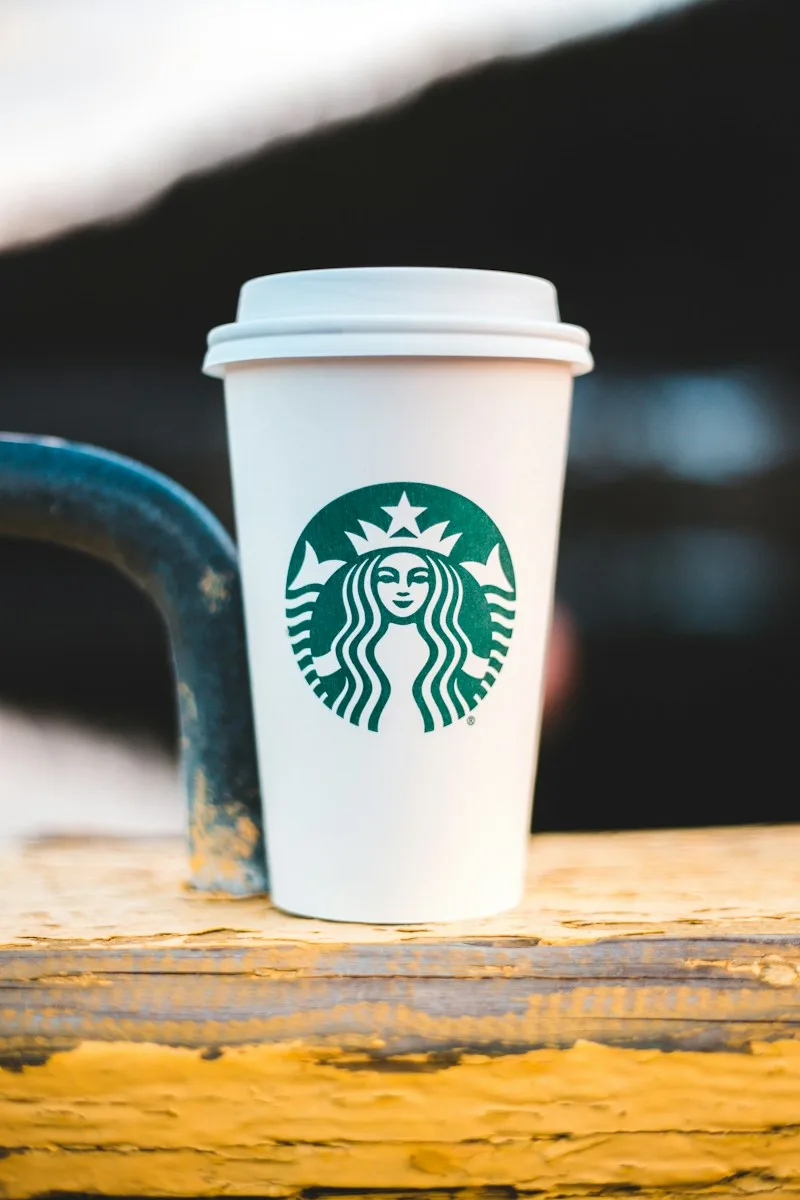 Starbucks takeaway cup on a yellow wooden surface.